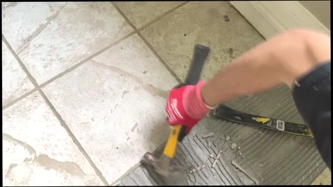 An unrecognizable man removes tiles from the floor with a hammer and tools. Stock Footage 206167746