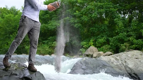 Unrecognizable man scattering ashes into the water ,beautiful nature mountain Stock Footage 247274182