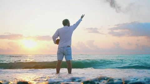 An unrecognizable man scatters ashes over the sea from a cremation urn Stock Footage 246745399