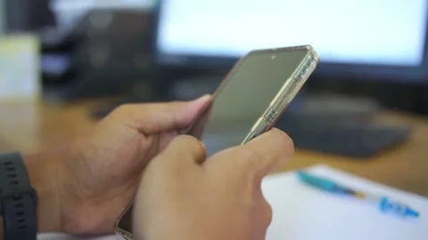 Unrecognizable man sitting at work place desk with smart phone in hands Stock Footage 322116110