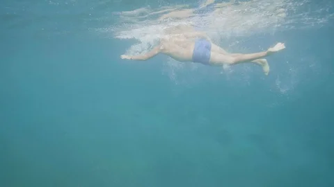 Unrecognizable man is swimming crawl in open water, underwater shot. Video stock 107136178