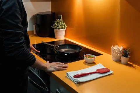 Unrecognizable man switching the induction in orange kitchen Stock Photos