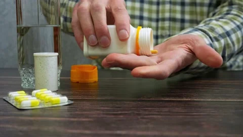 Unrecognizable man takes medicine while sitting at the table 動画素材 235932133