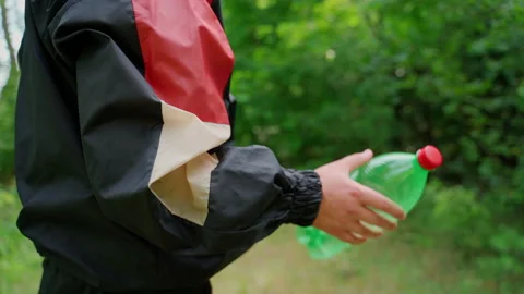 Unrecognizable man throw plastic bottle in nature. Forest pollution Stock Footage 158119438