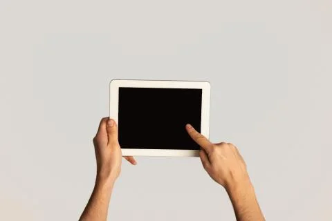 Unrecognizable man touching screen of modern tablet computer on light background Stock Photos