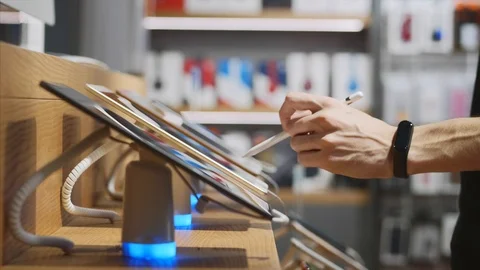 Unrecognizable man a trying a tablet with stylus in an electronics store Stock Footage 117834366