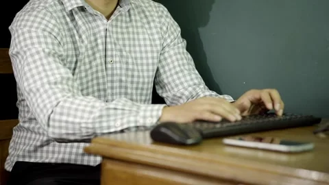 Unrecognizable Man types using computer keyboard and checks cell phone in office Stock-Footage 275349475
