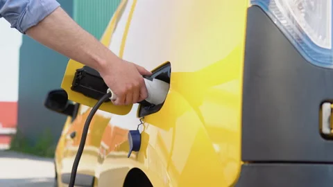 Unrecognizable man unplugs charging cable electric vehicle. Male hand Stock Footage 193458910