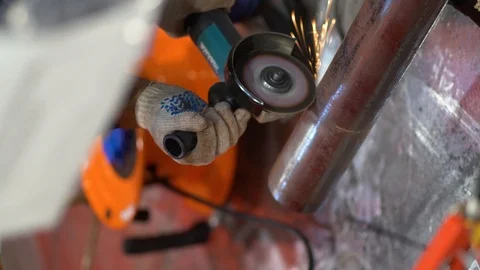 Unrecognizable man uses circular grinder, cuts small piece from metal pipe, saws Stock Footage 126358209