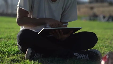Unrecognizable man uses tablet with digital pencil sitting on grass 스톡 동영상 147833724