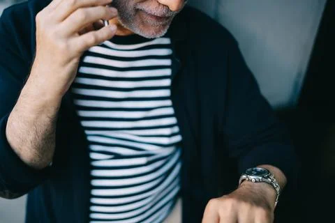 Unrecognizable man using cellular gadget and mechanic watch accessory while Stock Photos