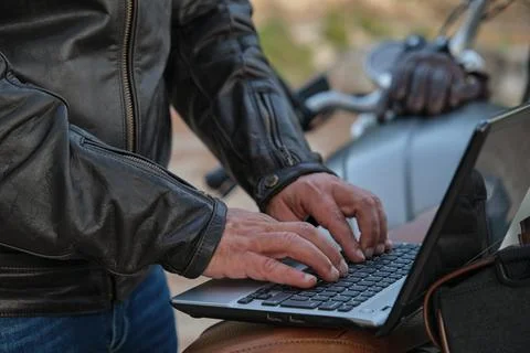 Unrecognizable man using a laptop while traveling with his motorcycle Stock Photos