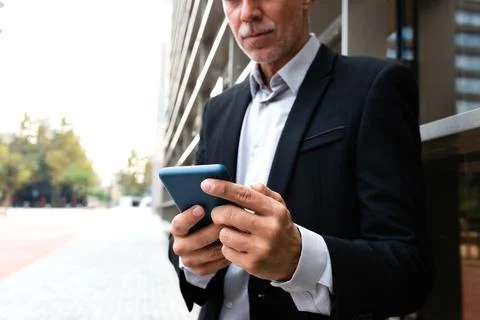 Unrecognizable man using mobile phone outside office.Copy space.Selective focus. Stock Photos