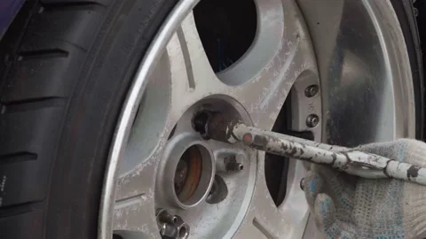 Unrecognizable man using a wrench tool to wheel nuts on a car. Close-up Stock Footage 130389120