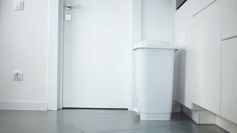 Unrecognizable man walks up to a white bin and throws out a paper towel at home Vídeos de archivo 121002313