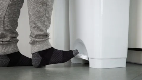 Unrecognizable man walks up to a white bin and throws out a paper towel at home Stock Footage 121002359