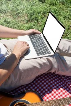 Unrecognizable man in white pants outside having picnic and using laptop, wor Stock Photos