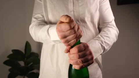 An unrecognizable man in a white shirt opens champagne Stock-Footage 311689701