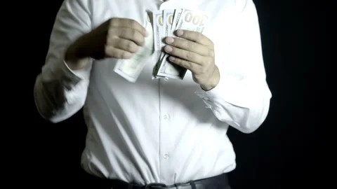 Unrecognizable man in white shirt throwing $100 bills on a black background Stock Footage 272193192