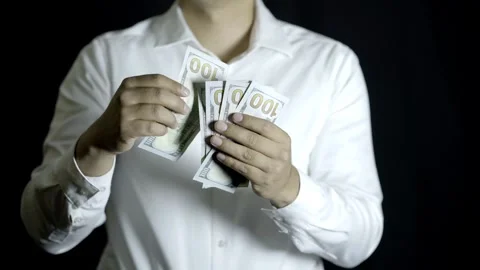 Unrecognizable man in white shirt throwing $100 bills on a black background Stock Footage 272193218