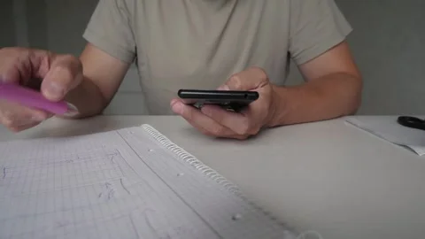 An unrecognizable man writes notes while checking messages Video stock 321204181