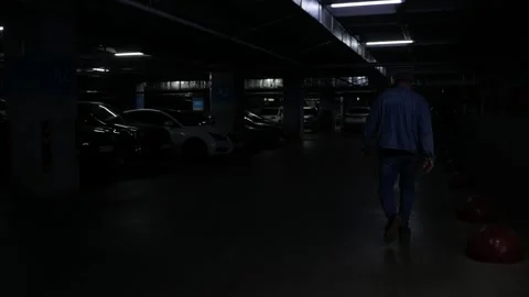 Unrecognizable maniac walking through a dark parking lot. Killer, spooky murdere Stock Footage 274187655