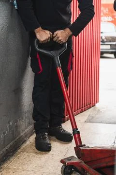 Unrecognizable mechanic using a jack to lift car. Automobile mechanics concep Stock Photos