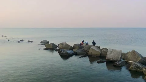 Unrecognizable Men with Fishing Rods Sit on Rocks with Fishing Tools.  Stock Footage 204064553