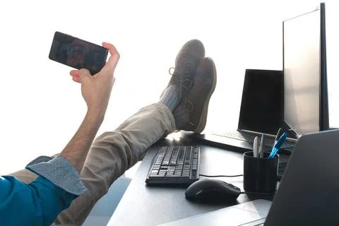 Unrecognizable middle-aged man in office. relaxing feet on desk. Video call Stock Photos