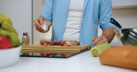 Unrecognizable modern man salting steaks on cutting board while preparing them Stock Footage 147280321