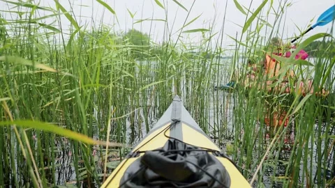 Unrecognizable mother with kid does kayaking by yellow plastic sports boat Stock Footage 152257020