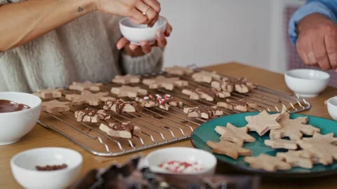 Unrecognizable multi ethnicity couple decorating sweet cookies with colorful spr Stock Footage 218775319