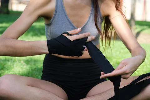 Unrecognizable no binary person wearing muay thai hand wraps sitting on grass Stock Photos