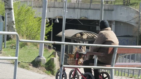Unrecognizable Old Man with Walker Resting on Bench next to Tram Stop Stock Footage 220676369