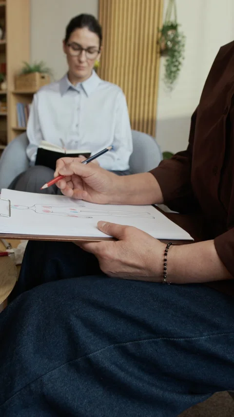 Unrecognizable Patient Drawing on Human Body Diagram during Therapy Session Stock Footage 330667776