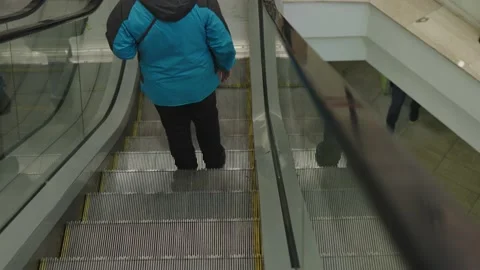 Unrecognizable people back view going down using escalator steel stairs blue Stock Footage 221519359