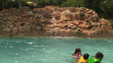 Unrecognizable People in Lazy River Floating By Rock Waterfall Stock Footage 24714656