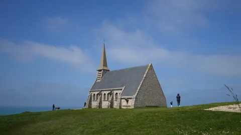 Unrecognizable people walking around small old chapel in Etretat found on top of Stock Footage 241917217