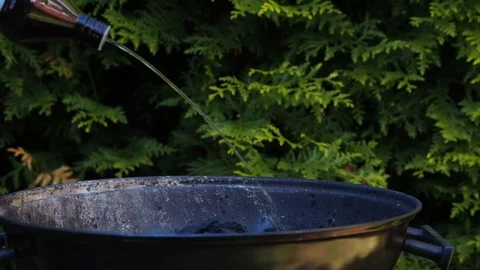 Unrecognizable person adding lighter fluid onto grill coal Stock Footage 76234942