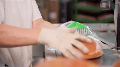 Unrecognizable person packing cut bread after long loaf cutting machine Stock Footage 250268763