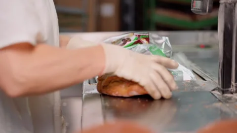Unrecognizable person packing cut bread after long loaf machine. Slow motion Stock Footage 250276445