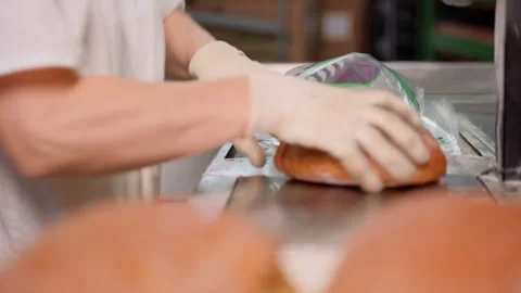 Unrecognizable person packing cut bread at factory indoors. Slow motion Stock Footage 250276695