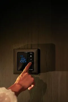 Unrecognizable Person Pointing and using Thermostat on black Wall Stock Photos