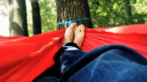 Unrecognizable person resting inside a red hammock in a park Stock Footage 91174829
