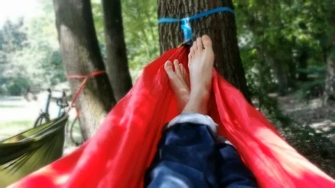 Unrecognizable person resting inside a red hammock in a park Video stock 91174837