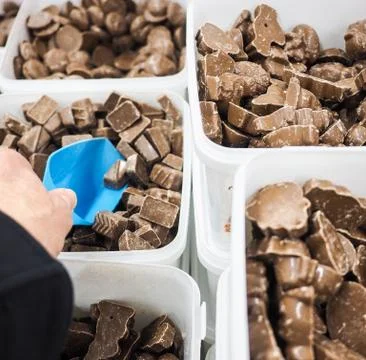Unrecognizable person scooping assorted pieces of chocolate Stock Photos
