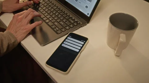Unrecognizable Person Typing on Laptop Receiving Push Notifications on Phone Stock-Footage 344873314