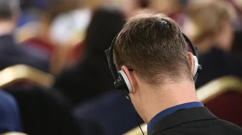 Unrecognizable person using in ear headphones for translation during event Видео 68881582