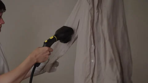 Unrecognizable person using handheld clothes steamer, removing wrinkles from Stock Footage 318517965