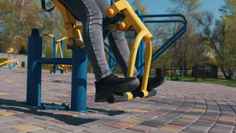 Unrecognizable Person Using Yellow Outdoor Leg Press Machine in a Park Stock Footage 333824848